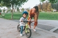 A little boy learning how to ride his bike in the park while wearing a helmet.  - PhotoDune Item for Sale