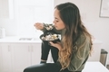A woman sitting on a counter, eating a healthy take out meal in a bright white kitchen.  - PhotoDune Item for Sale