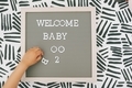 A child's hand arranging letters on a letter board that says 'welcome baby boo 2'.  - PhotoDune Item for Sale
