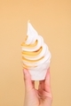 An orange twist soft serve ice cream cone against an orange wall.  - PhotoDune Item for Sale