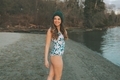 A woman standing on the beach in a one piece swim suit in winter.  - PhotoDune Item for Sale