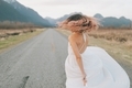 A woman with pink hair in a white dress twirling on a street in the mountains. - PhotoDune Item for Sale