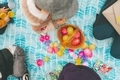 people gathered around a basket full of brightly coloured eggs.  - PhotoDune Item for Sale