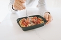 Hands eating a take out lunch of spaghetti and meatballs on a white counter. - PhotoDune Item for Sale