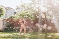 A woman holding a little boy while running through the sprinkler on a sunny summer day.  - PhotoDune Item for Sale