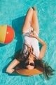 A woman in a white swim suit laying in a pool in the summer. - PhotoDune Item for Sale