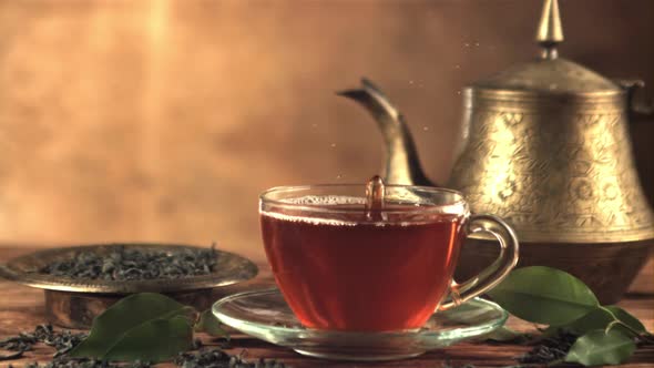 Super Slow Motion in a Full Cup with Tea Drops a Drop