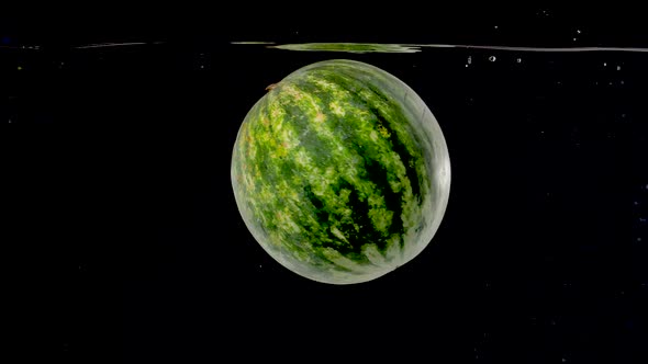 Colorful watermelon being dropped into water in slow motion.