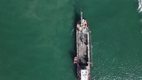 A large industrial dredging vessel pumping tons of sand into the ships storage area for a coastal re