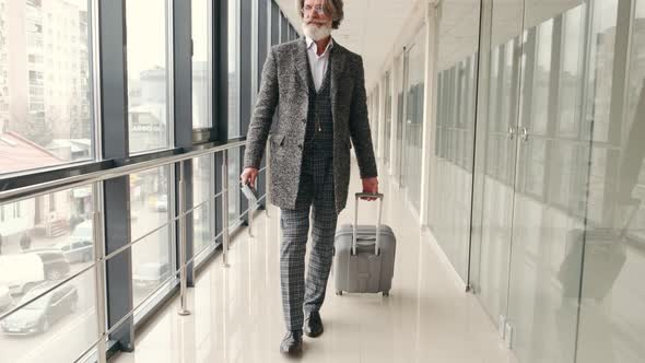 Old Hipster Man in Grey Suit with Suitcae Going Along the Airport Hall