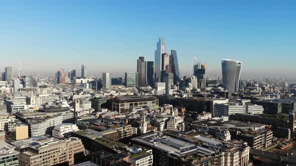 Reverse aerial view of London's Financial District skyscrapers on a sunny hazy day