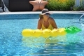 Woman yellow pineapple float at her backyard swimming pool  - PhotoDune Item for Sale