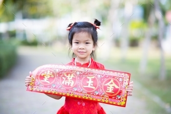 greeting card that means Wealthy and happy. Happy children smile sweetly. Child wear red cheongsam in garden. Kid aged 5 years old.