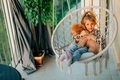 little girl hugging poodle dog at home on the balcony in a hammock chair with cotton fringe sunset - PhotoDune Item for Sale