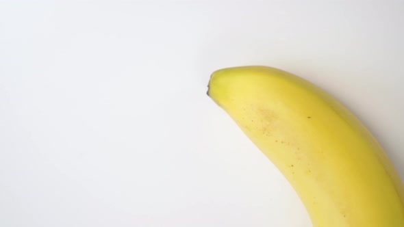 Bright yellow ripe banana moves on a white background.