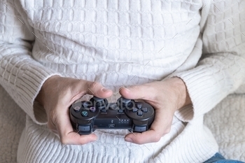 an in a white sweater playing a video game. A person using a video game controller to relax and relieve stress at home while staying at home. Home entertainment concept. Selective focus.