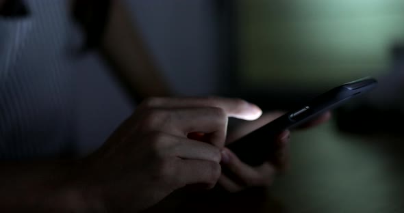 Woman using cellphone in the living room at night
