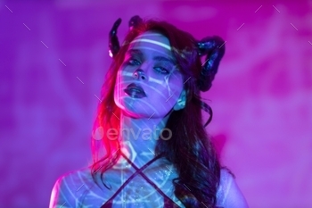 Girl with horns on head in neon light.