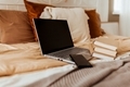 laptop on cozy bed with books in bedroom - PhotoDune Item for Sale
