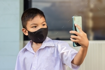 child boy wearing  mask for prevent Covid-19 disease and corona virus. using a smart phone