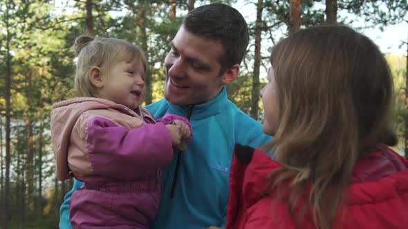 Young Parents with Little Daughter in Forest or Park Outdoor Portrait