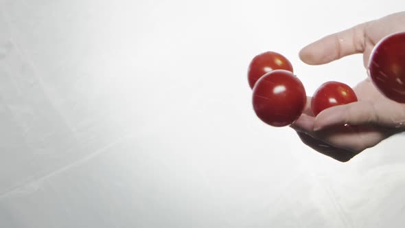 Person Throws Handful of Tasty Cherry Tomatoes Into Water