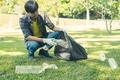 garbage collection, Man's hands pick up plastic bottles, put garbage in black garbage bags to clean  - PhotoDune Item for Sale
