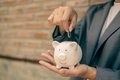 Asian businesswomen hold piggy banks and put coins in piggy banks to save money with coins to step - PhotoDune Item for Sale