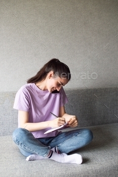 A young woman holding a cell phone nearby, talking on the phone with her boss, writes in a notebook