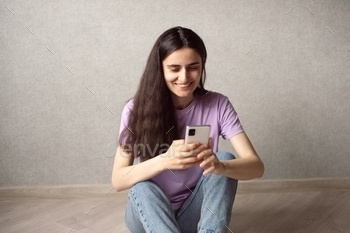 A young girl is sitting and looking at the phone