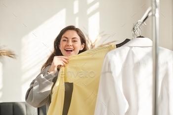 happy woman in store found the right size of clothes. girl in store is looking for new shirt