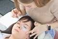 woman cosmetologist applying under eye patch to isolate eyelashes during lash extension procedure. - PhotoDune Item for Sale