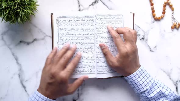 Top View of Young Man Reading Holy Book Quran on Table