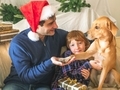 Dad and son in santa claus caps with their dog on christmas holidays. - PhotoDune Item for Sale
