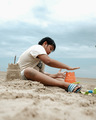 A boy build castle from the sand at the beach - PhotoDune Item for Sale