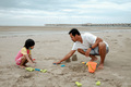 A family having a picnic at the beach, and helping their kids build castle from the sand - PhotoDune Item for Sale