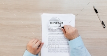 hands hold a magnifying glass and study the contract. The document lies and the pen lie on a wooden table.
The concept of studying a contract before signing.
real estate, contract study, insurance, training, work, get a job, rental points, house, leasing, property inspection, contract, before signing, table, contract house, real estate loan, documentation, rental concept, real estate, lease agreement, wooden table, documents, table,profession,insurance,