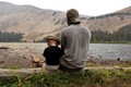 A father and son enjoying the mountain views together while sitting on a log at the lake.  - PhotoDune Item for Sale