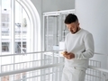 Young man in a stylish white modern interior checks the news in his mobile phone - PhotoDune Item for Sale