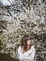 Cute girl with bangs on the background of flowering apple trees in spring in a white jacket - PhotoDune Item for Sale