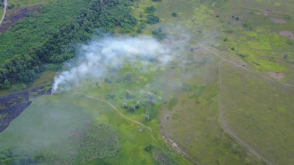 Flight Through a Smoke Over Burning Green Field, Wild Fire in Nature Landscape, Aerial Footage From
