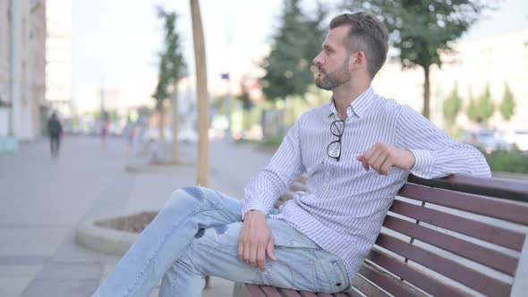 Young Adult Man Looking at Camera While Sitting on Bench