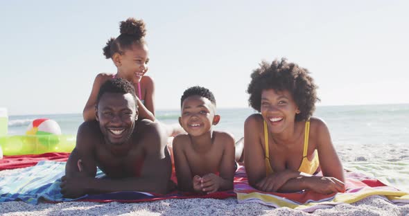 Portrait of smiling african american family lying on sunny beach