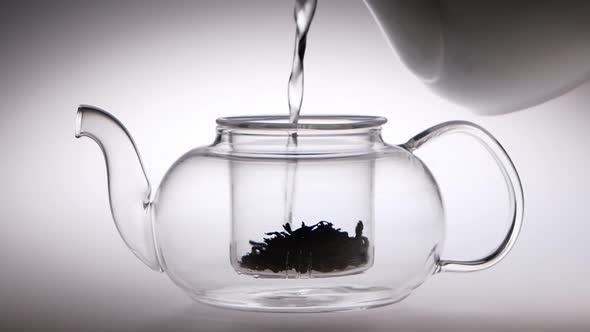 Into Transparent Teapot with Tea Leaves Is Poured Boiling Water