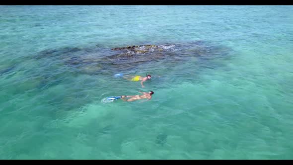 Two people suntan on tranquil resort beach wildlife by blue lagoon and white sand background of the 