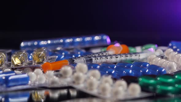 Some Different Contraceptive Pills and Two Syringes, Rotation, Reflection, on Black, Back Light