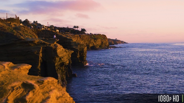 Woman Sitting on Rocky Sunset Cliffs Coastline in San Diego, California