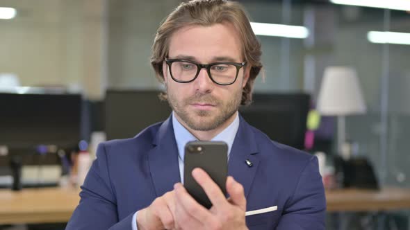 Portrait of Businessman Using Smartphone in Office