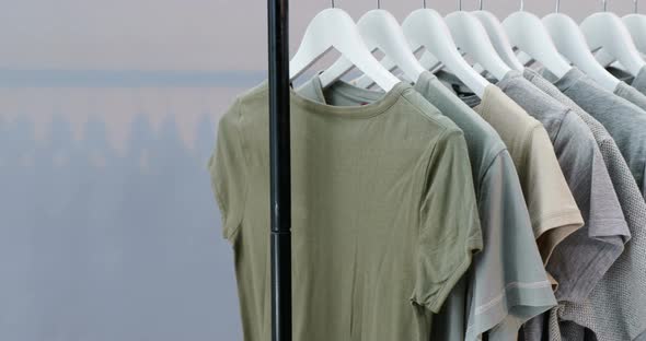 Various t-shirts arranged in a row on cloth rack 4k