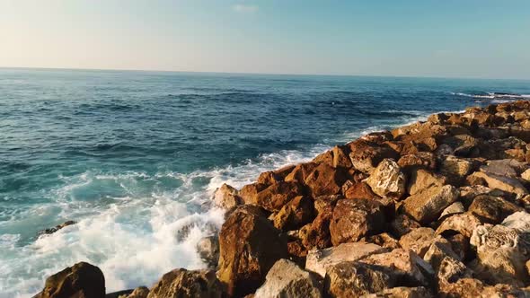 Blue waves breaking over the rocky Jaffa breakwater